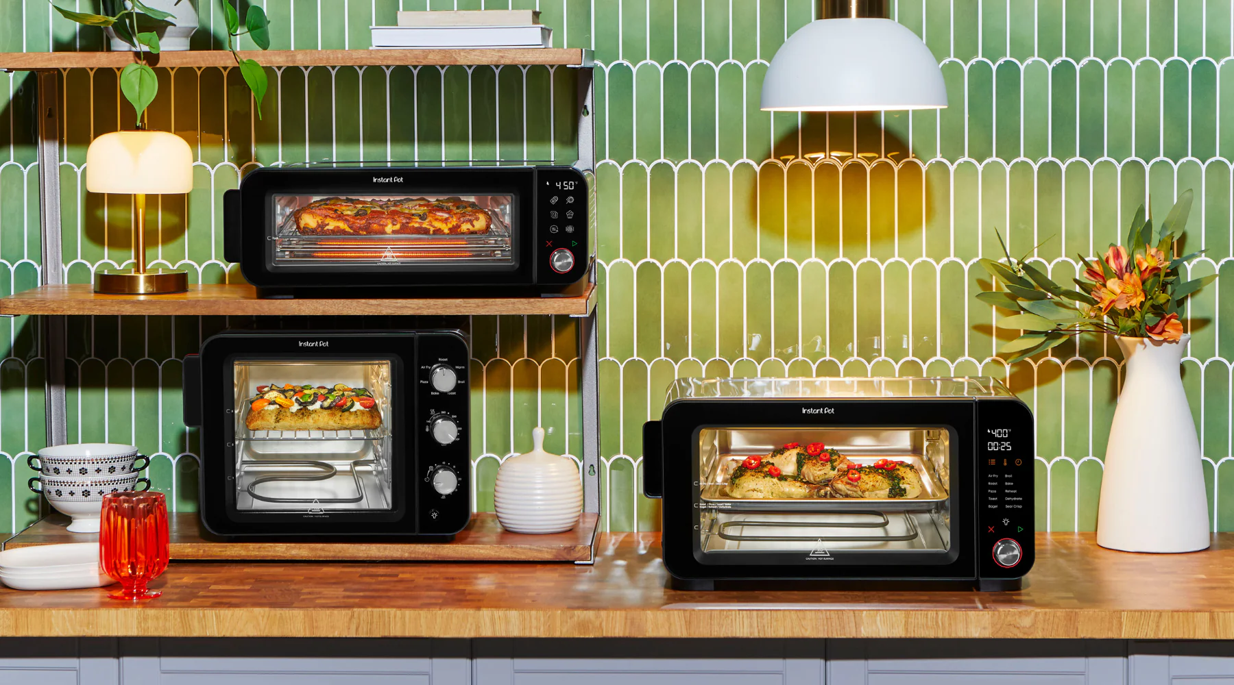 A bright, modern kitchen setup featuring three Instant Pot countertop ovens against a glossy green tile backsplash